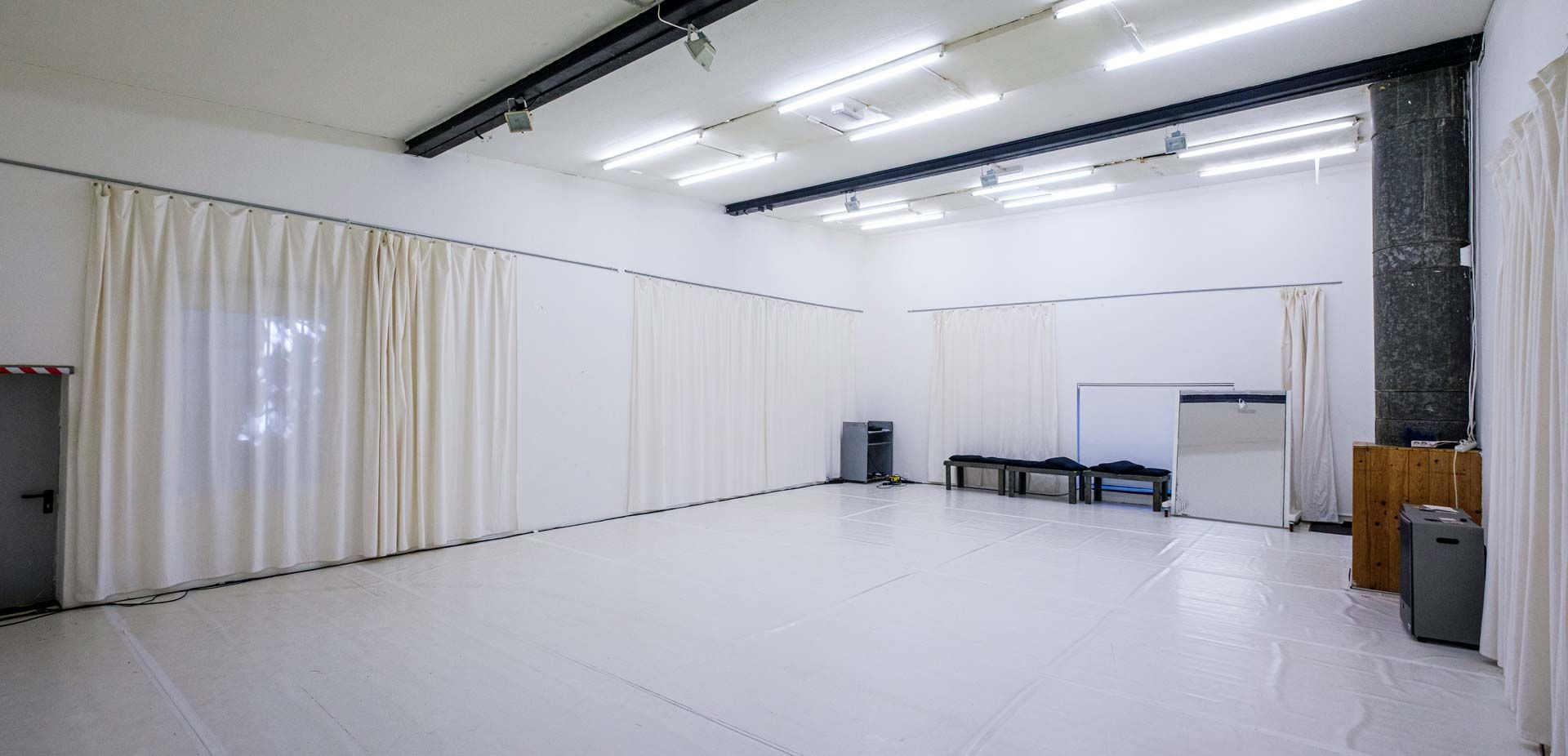 Studio 2 / White Cube bei Barnes Crossing mit hellem Tanzboden, weißen Wänden, teilweise abgehängt mit weißen Vorhängen, und Bänken an einer Wand.