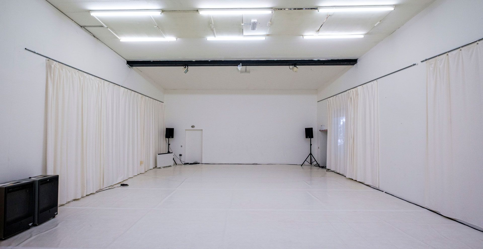 Studio 2 / White Cube bei Barnes Crossing mit hellem Tanzboden, weißen Wänden, teilweise abgehängt mit weißen Vorhängen, undMusikanlage.